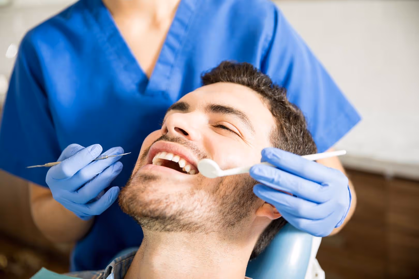 Man Receiving Treatment From Dentist In Dental Clinic